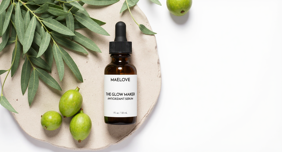 Maelove Glow Maker serum on a stone tray with eucalyptus sprigs and green botanicals, overhead flat lay